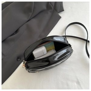 Internal view of a glossy black crossbody bag showing storage for daily essentials