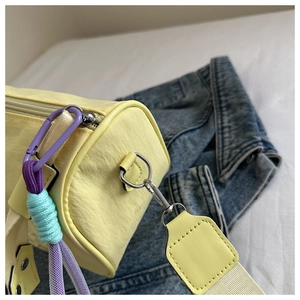 Detail van gele cilindertas met paarse metalen haak en blauw touwdecor op denim