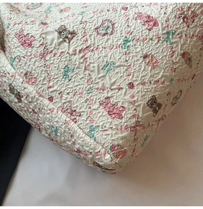Détail du tissu gaufré blanc du sac fourre-tout avec motifs de lapins et d'oursons mignons