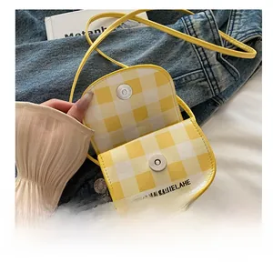 Detail of the magnetic metal clasp on yellow gingham shoulder bag with text print