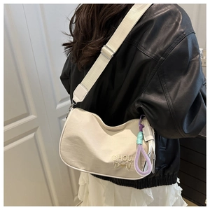 Detail of off-white crescent crossbody bag with adjustable strap and charm on model