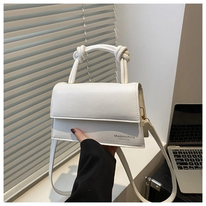 Detail of white faux leather crossbody bag with knot handle and printed logo lettering