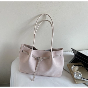 Detail of light beige woven tote bag with belt buckle on office desk with laptop