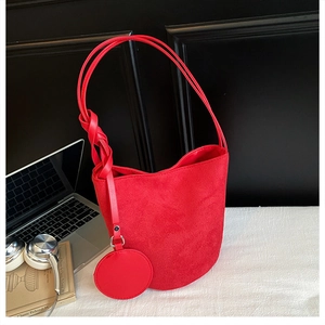 Macro view of red suede bucket bag with round coin purse and stylish knot handle details