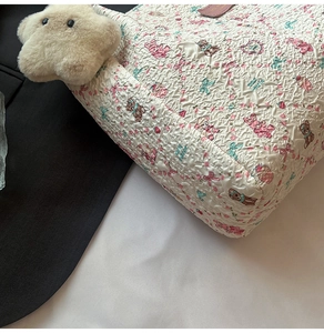 Gros plan sur le sac fourre-tout blanc avec texture plissée, motifs ours et pendentif étoile