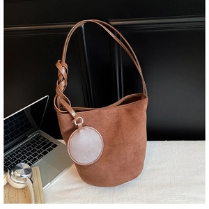 Detail of suede bucket bag with woven knot strap and circular coin purse charm