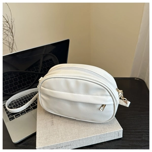Close-up of a white oval crossbody bag with a decorative fold and zip closure