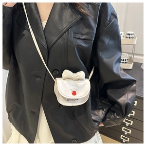 Mini white crossbody bag with cute puppy print and bow detail shown on model