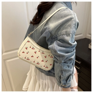 Détail d'un sac à bandoulière blanc tendance avec imprimé cerise et texture en cuir