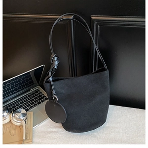 Detail of black suede bucket bag with knotted shoulder strap and round mini coin purse charm