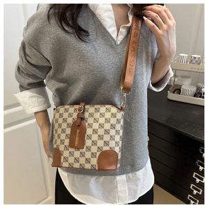 Détail d'un sac seau imprimé avec large bandoulière en tissu et étiquette en cuir