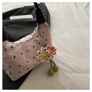 Detailed shot of pink pleated handbag with black K prints and floral charm