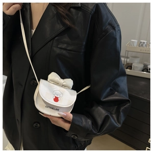 Mini white crossbody bag with cute puppy print and bow detail on black leather jacket
