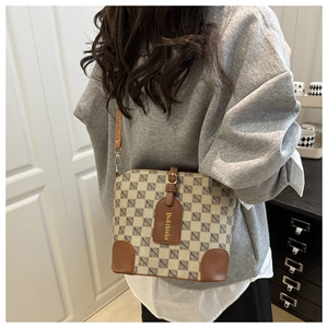 Détail de l'imprimé logo et de l'étiquette en cuir doré sur le sac à bandoulière