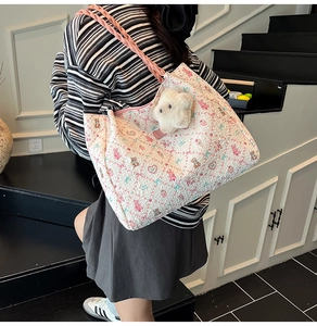 Gros plan d'un sac cabas matelassé blanc avec motifs floraux et pendentif ours doux