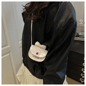 Mini white crossbody bag with cartoon puppy print and bow detail shown on a model