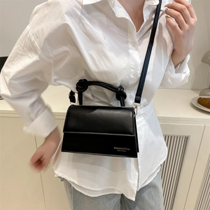 Minimalist black square crossbody bag with unique knotted handle and golden hardware details