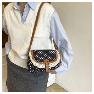 Dettaglio borsa retrò in tela a pois con bordo in pizzo e tracolla in pelle marrone