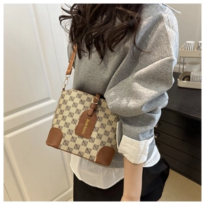 Close-up of printed bucket bag with brown leather trim and golden hardware detail