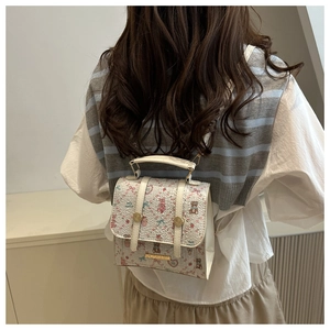 Detail of a creamy white backpack featuring cute cartoon bear and strawberry patterns