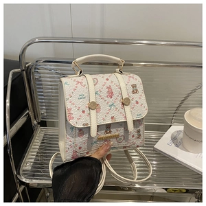 Close-up of white mini backpack with pink cartoon patterns and golden metal buckle details
