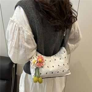White textured shoulder bag with black letter K embroidery and floral charms