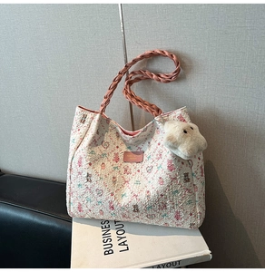 Detail of floral print tote bag with woven pink handle and plush bear charm accent