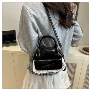 Detail of glossy black patent leather bag with white lace trim and bow accent