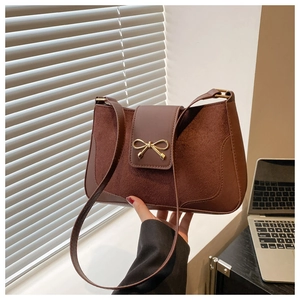 Close-up of brown patchwork shoulder bag with golden bow clasp and retro PU texture