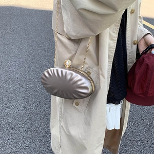Oval metallic evening clutch bag with pleated texture and pearl clasp in champagne gold