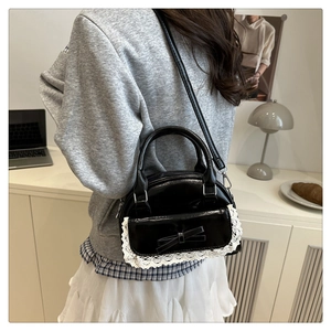 Detail of black bowling bag with lace trim and bow, shown on shoulder in interior setting