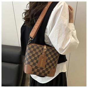 Détail d'un sac seau vintage à damier avec finitions en cuir et large bandoulière