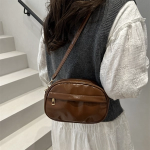 Brown patent leather shell crossbody bag with gold hardware and minimalist retro design
