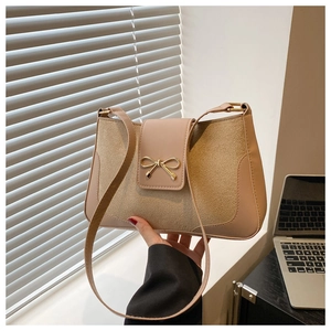 Detail of minimalist shoulder bag featuring a golden bow buckle and dual-texture design