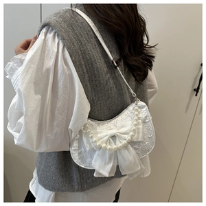 Detailed view of white embossed handbag featuring pearl handle and large satin bow