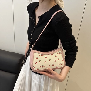 Sac sous le bras à imprimé cerise avec bordure rose porté par un mannequin chic