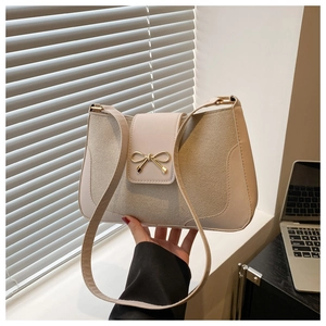 Detail of apricot shoulder bag featuring elegant golden bow metal buckle and mixed textures