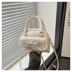 Detailed close-up of cream white bowling bag with lace trim and bow accent