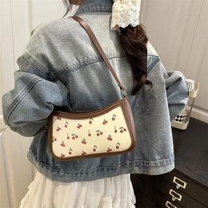 Sac sous le bras rétro à imprimé cerise avec garniture en cuir marron porté par un modèle