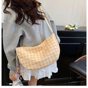 Detail of yellow checkered hobo bag with cute bear embroidery and heart patterns