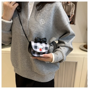 Close-up of mini checkered crossbody bag with black bow and cute cartoon puppy print