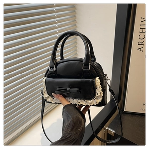 Detailed view of the black leather handbag featuring white lace trim and a small bow