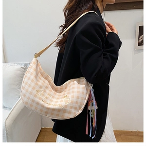Detail of embroidered bear and heart pattern on beige plaid hobo bag with colorful tassels