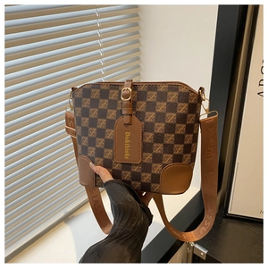 Macro detail of brown checkered bucket bag with embossed logo strap and leather tag