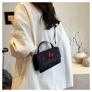 Detailed back view of a black crossbody bag with cherry prints and 3D cherry accents