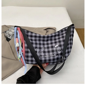 Detail of checkered hobo bag with cartoon prints and colorful ribbon tassel decoration
