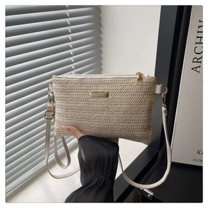 Detail of the woven straw crossbody bag featuring golden hardware and herringbone texture