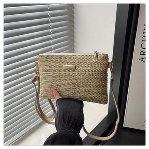 Detail of straw woven crossbody bag with metal plaque, zipper closure and adjustable strap