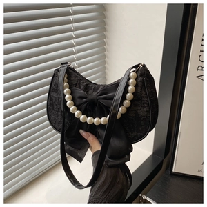 Detail of black crescent bag featuring lace texture, satin bow, and pearl strap