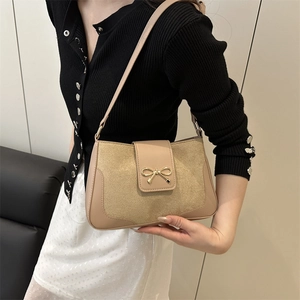 Elegant beige crossbody bag with metal bow accent and leather suede patchwork details